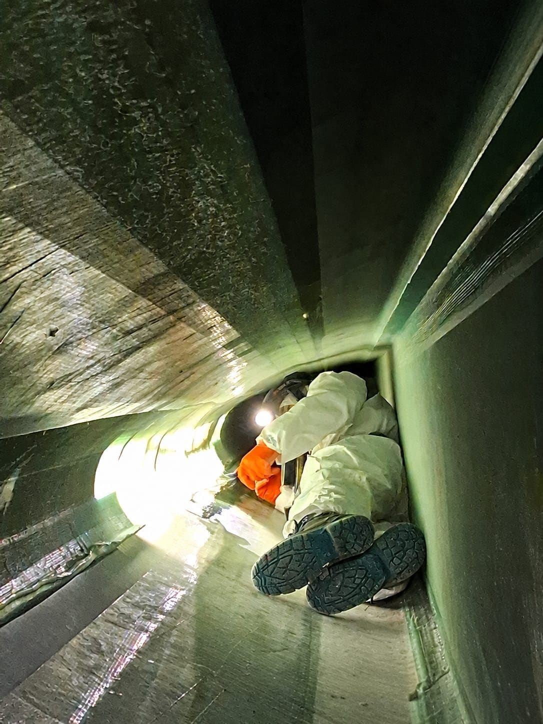 Technician working inside a wind turbine blade during internal repair