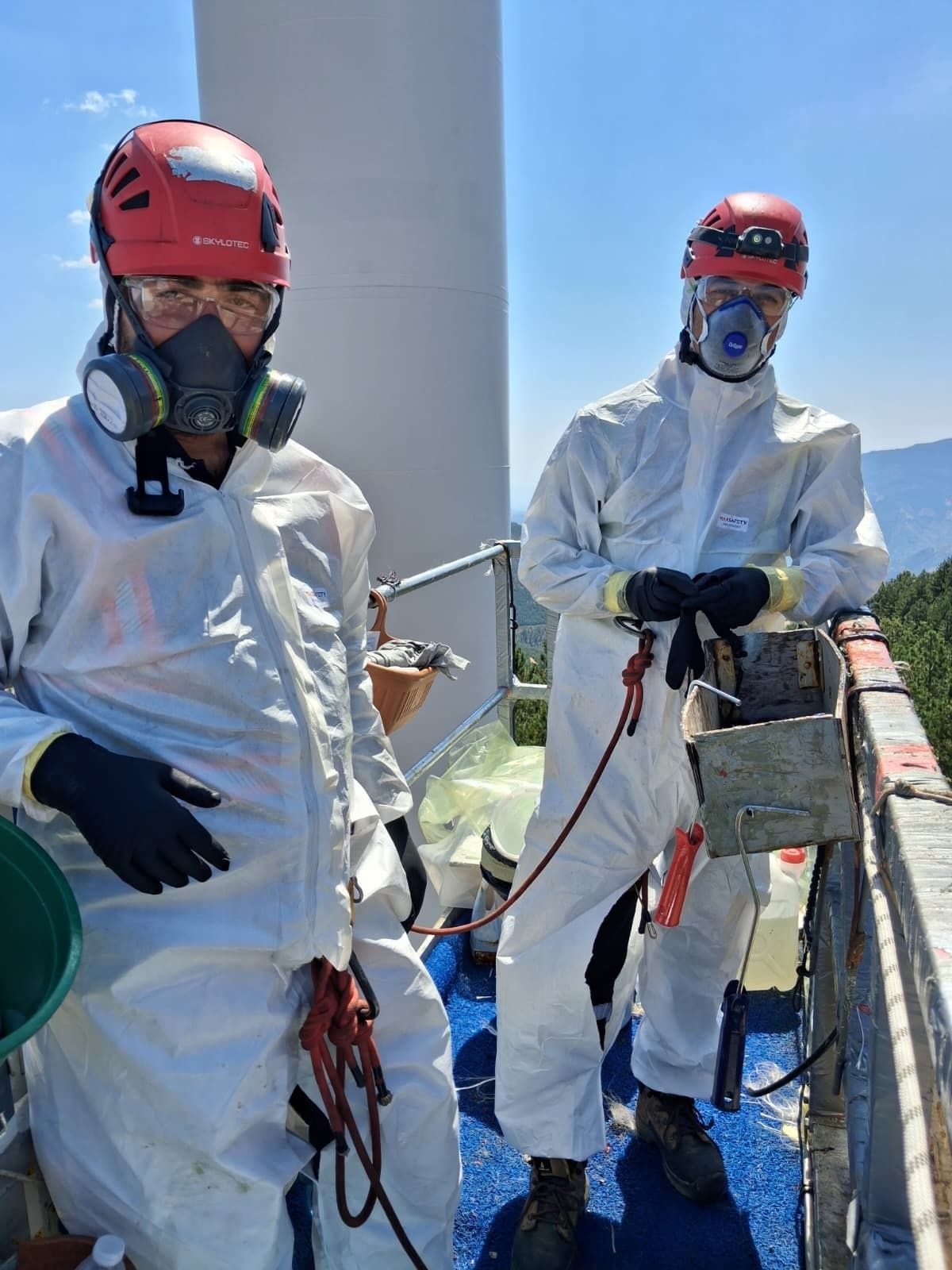 Blade repair team on an access platform in full PPE at a wind turbine