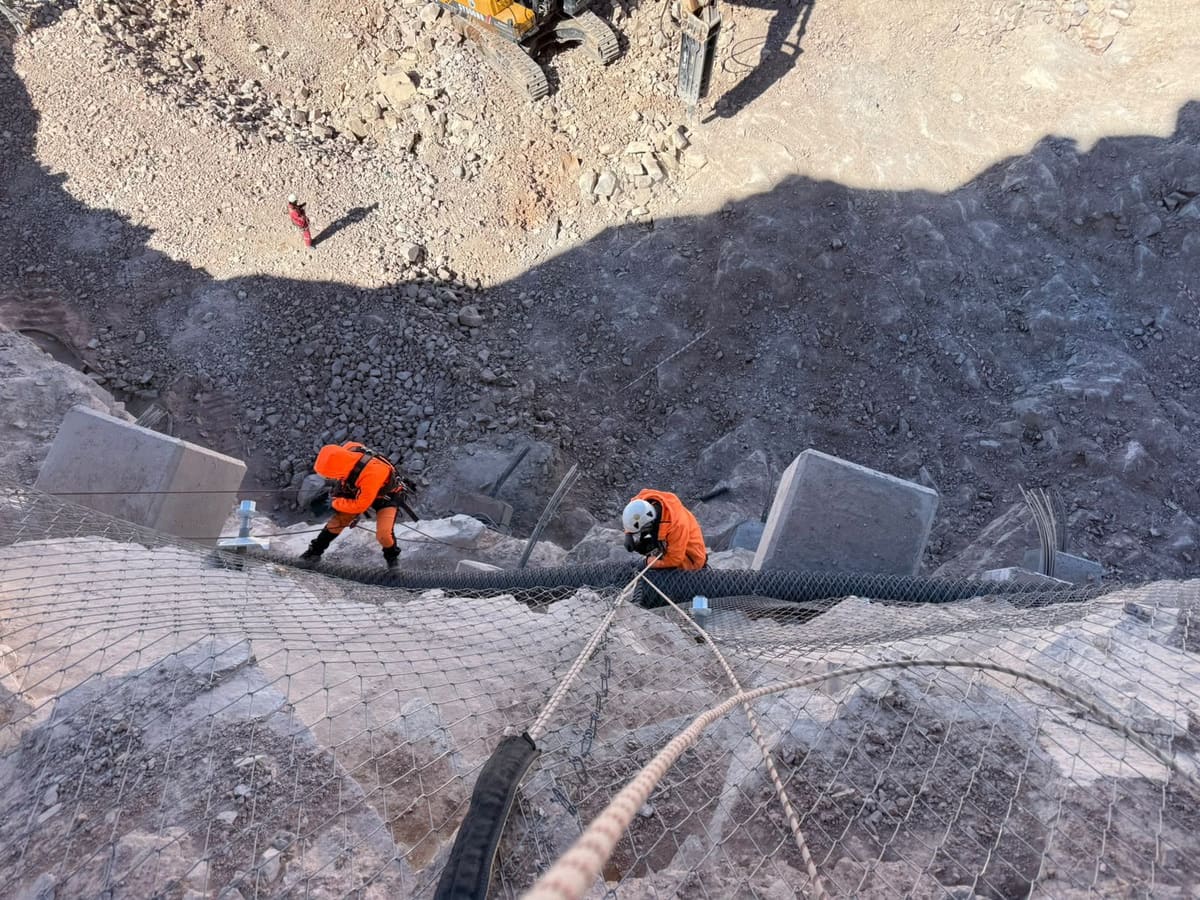 Crew installing steel mesh on a quarry slope, seen from above