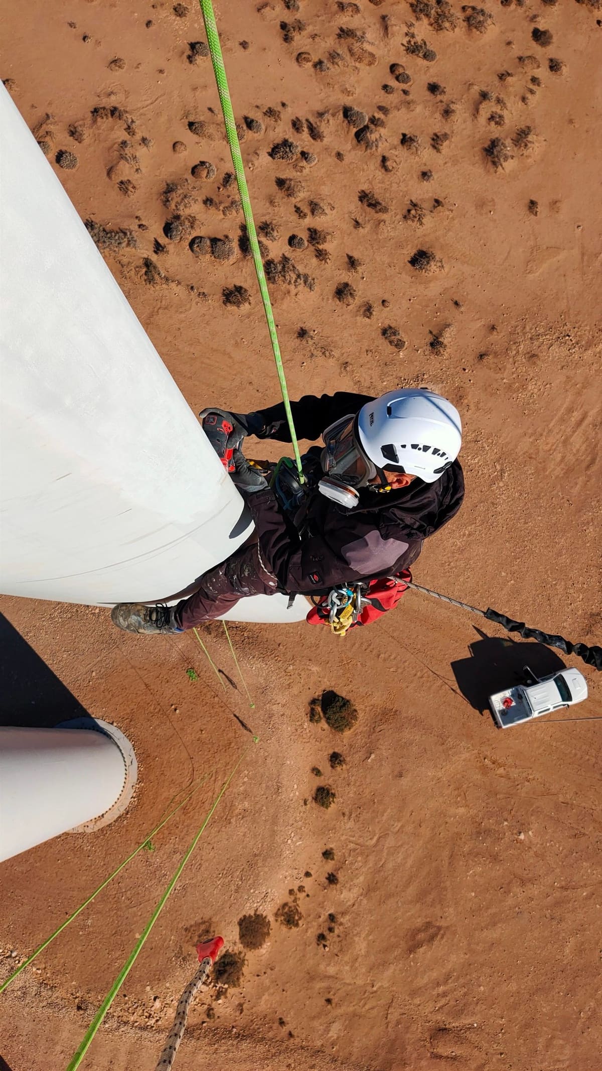 Rope access technician sanding a blade surface, seen from above