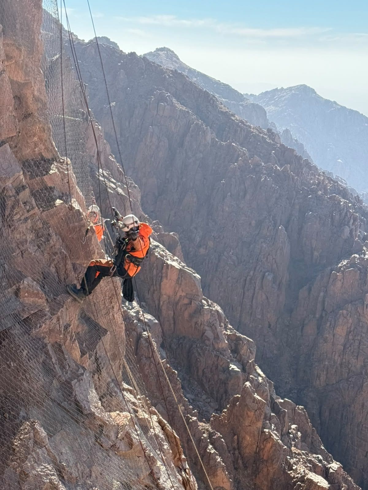 Rope access technician on a canyon rock wall