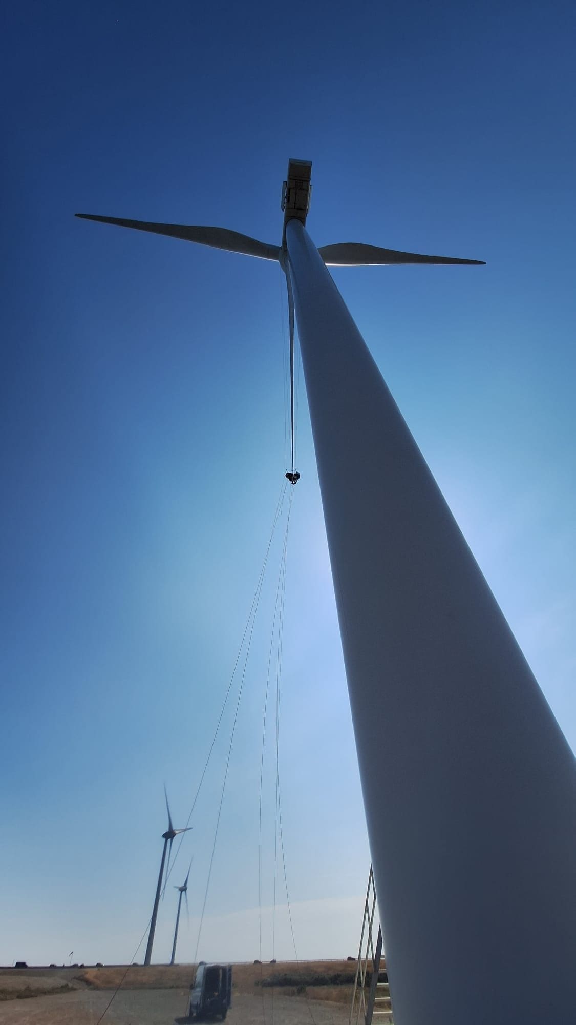 Rope access technician on a wind turbine tower against the sky