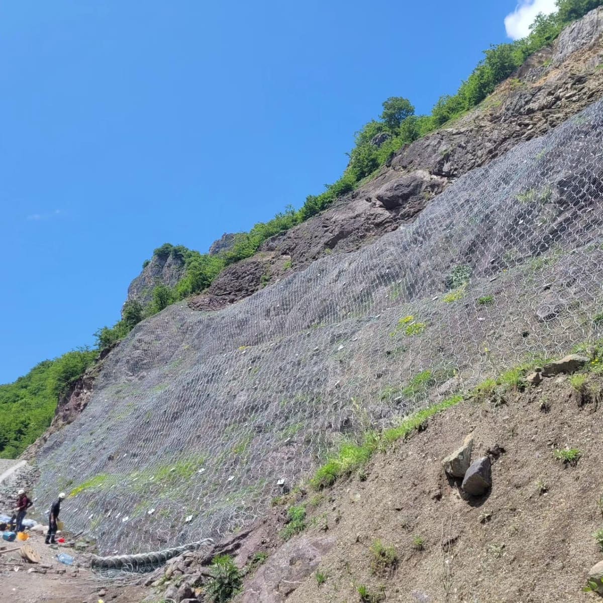 Rock slope covered with steel mesh drapery, wide view