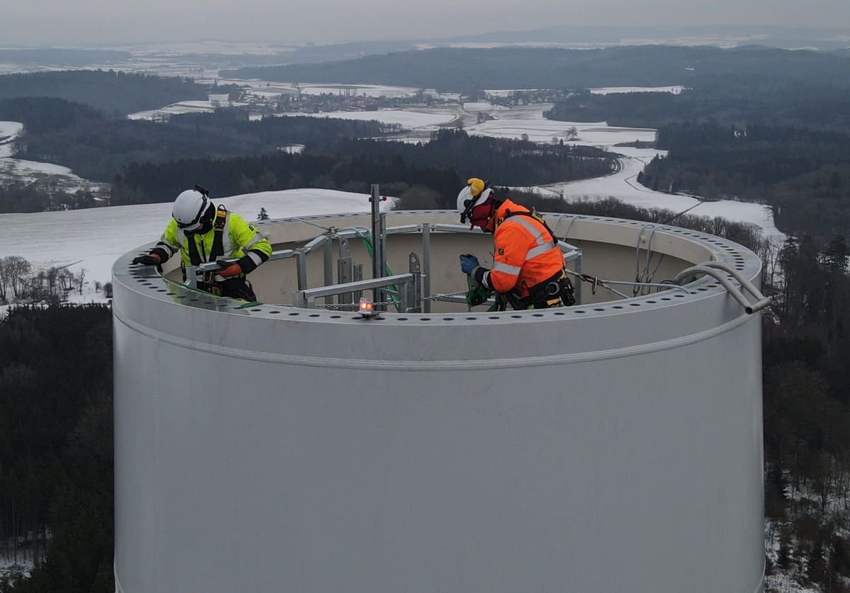 Technicians on a tower top flange in winter, drone view
