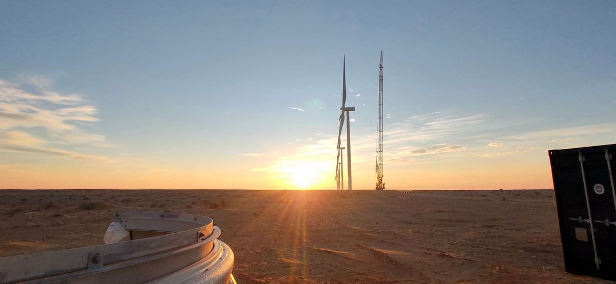 Wind turbine and erection crane at sunset